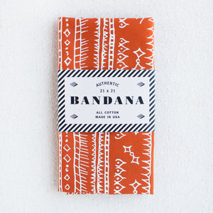 Maramalade orange bandana with white print, folded and attractively packaged with a natural kraft paper band printed with black ink.