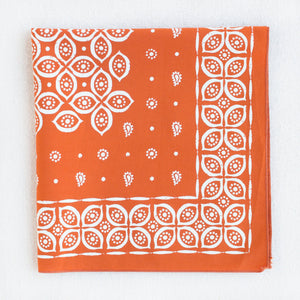 Marmalade orange bandana with stylized eye and paisley print. Folded into quarters.
