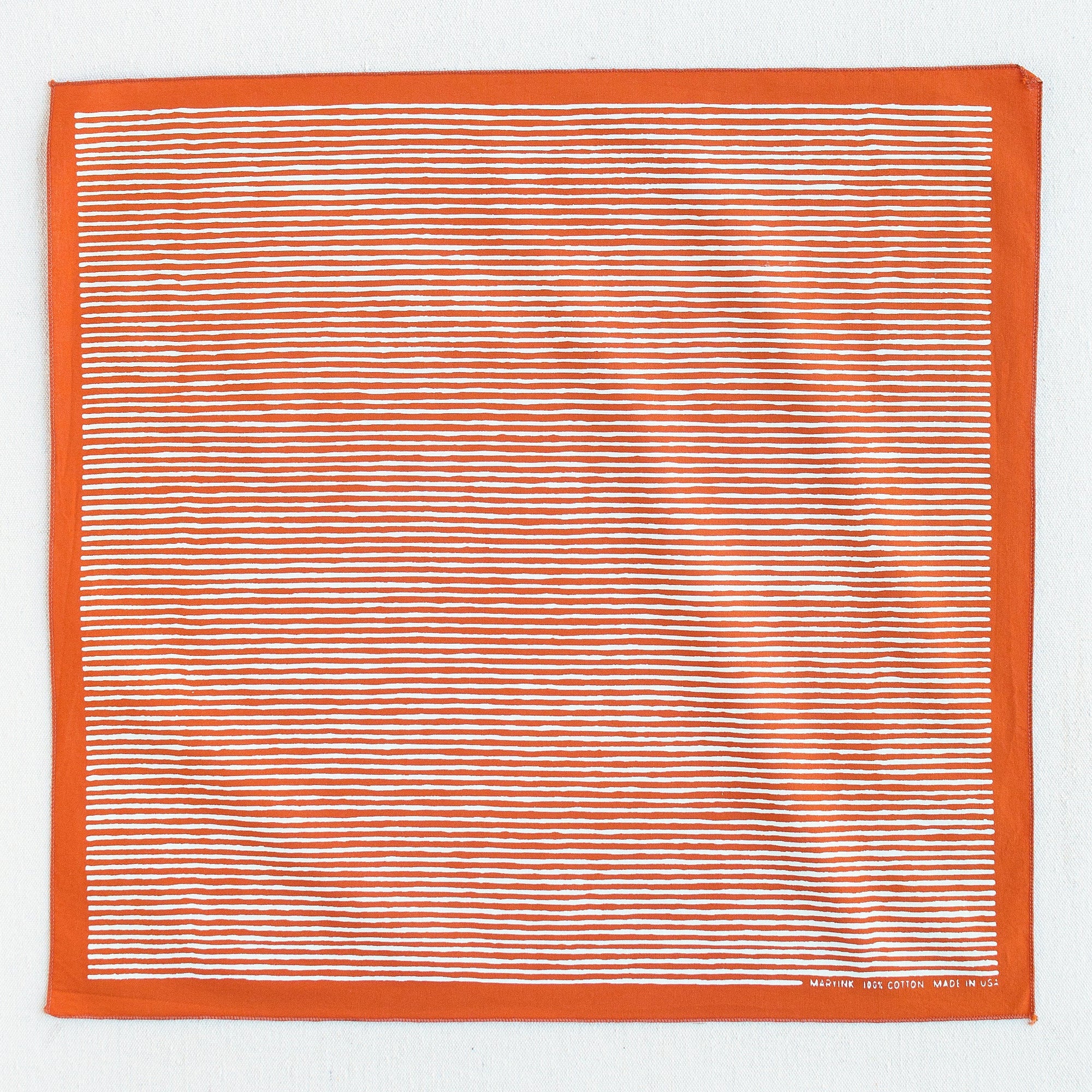 Burnt orange bandana with white striped screen print, shown open so the whole print is visible.